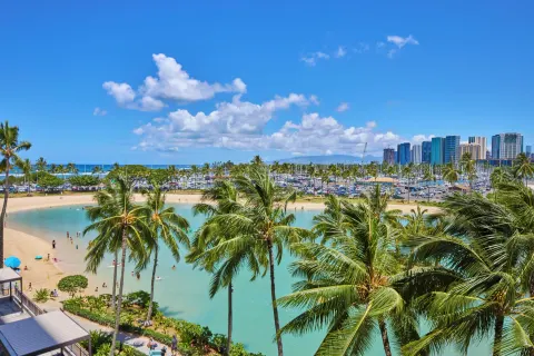 Rainbow Tower room view at Hilton Hawaiian Village Waikiki Beach Resort overlooking lagoon, palms, and skyline.