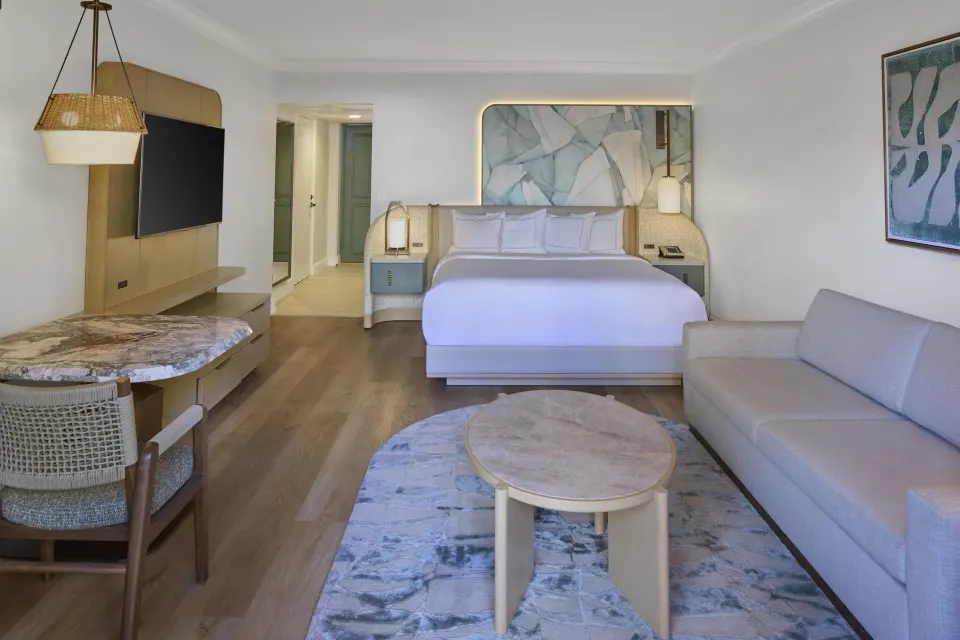 Ocean View Alii Tower king room with sofa and wall-mounted TV at Hilton Hawaiian Village Waikiki Beach Resort.