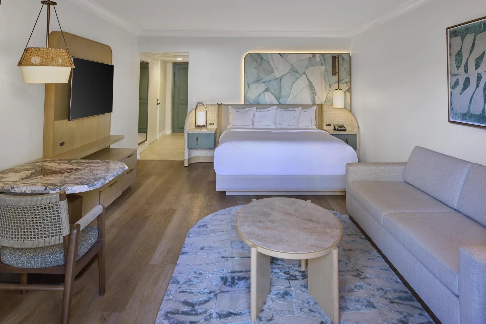 Ocean View Alii Tower king room with sofa and wall-mounted TV at Hilton Hawaiian Village Waikiki Beach Resort.
