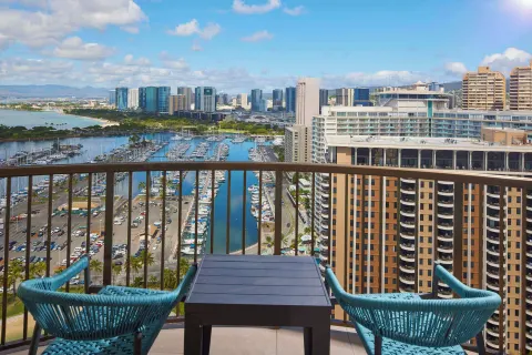 Balcony view from Hilton Hawaiian Village Waikiki Beach Resort over marina, city towers, and ocean.