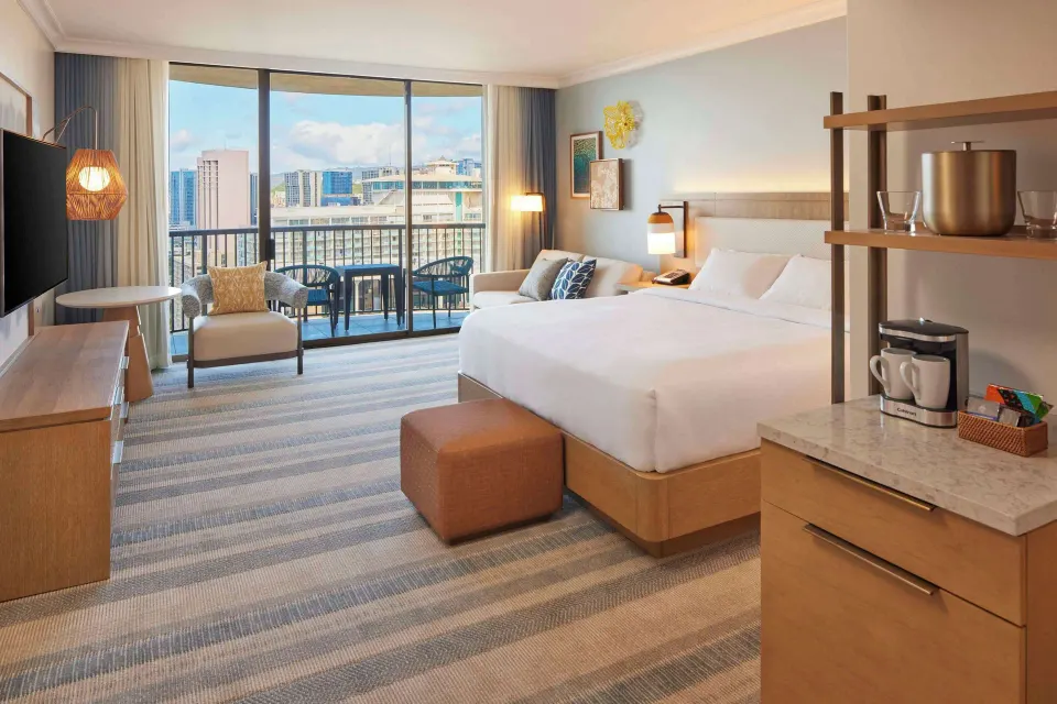 King room at Hilton Hawaiian Village Waikiki Beach Resort with sofa, coffee area, and city-facing balcony.