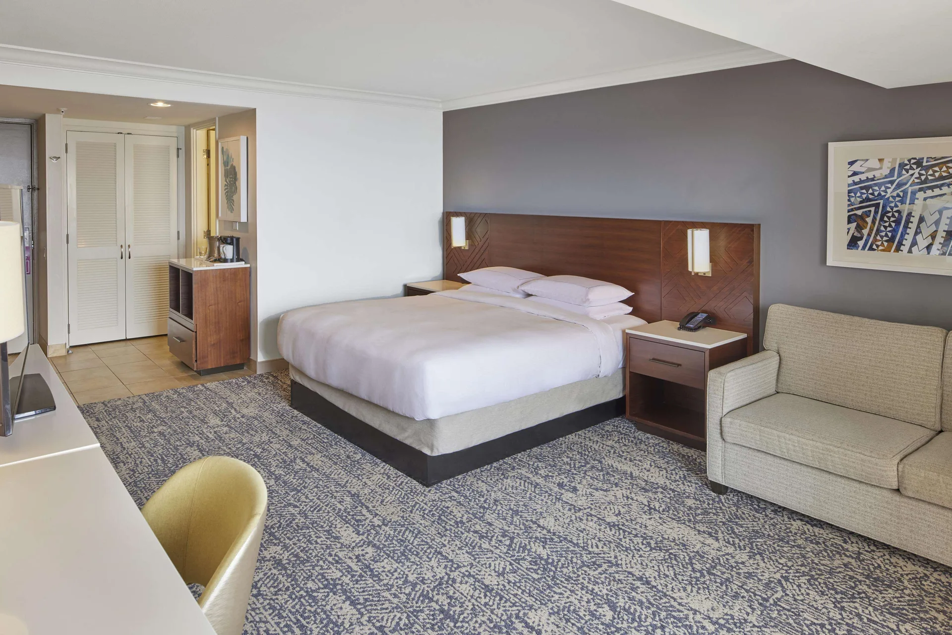 King bed guest room with sofa and entry area at Hilton Hawaiian Village Waikiki Beach Resort.