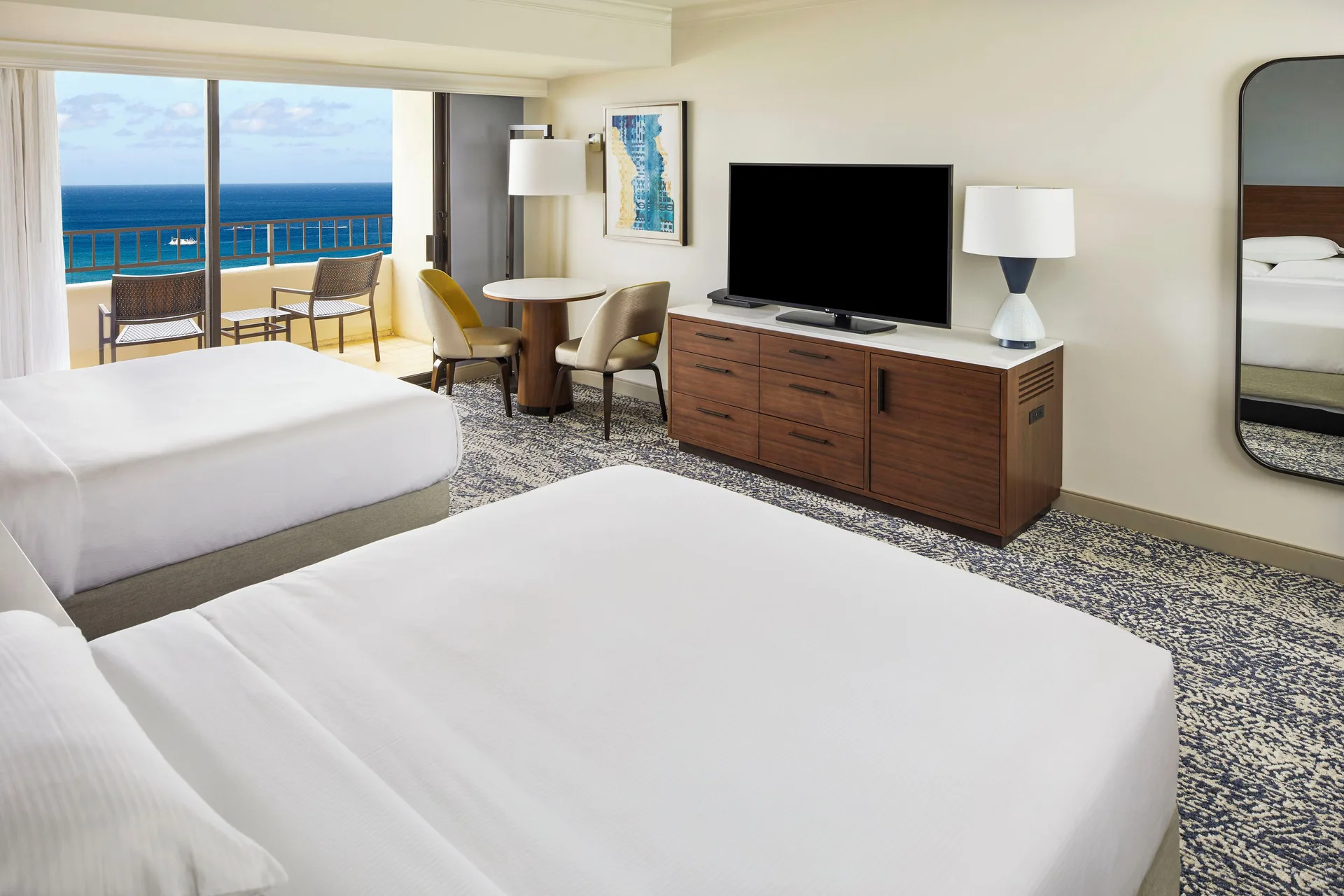 Ocean View Tapa Collection room with two beds, TV, dining table, and balcony at Hilton Hawaiian Village Waikiki Beach Resort.