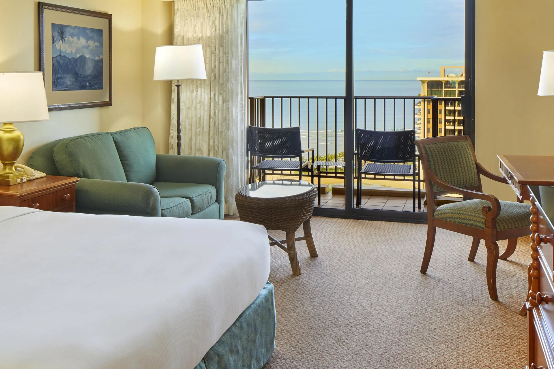 Ocean view room with bed, sofa, desk, and balcony at Hilton Hawaiian Village Waikiki Beach Resort.