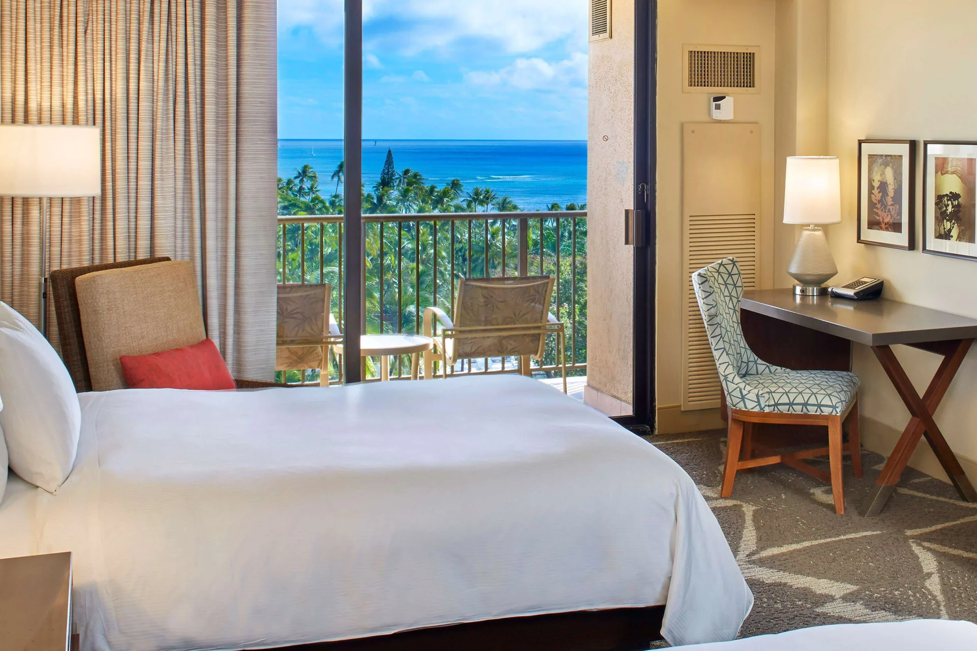Ocean view guest room with bed, desk, and balcony at Hilton Hawaiian Village Waikiki Beach Resort.