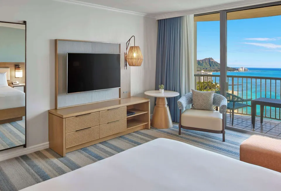 Renovated Rainbow Tower king room seating area and balcony view at Hilton Hawaiian Village Waikiki Beach Resort.