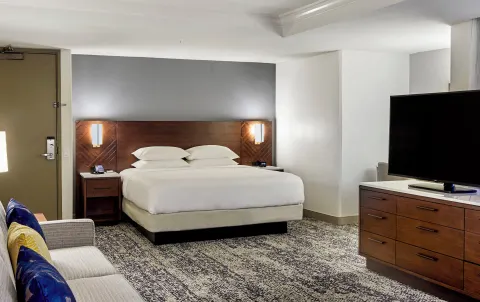 King resort view guest room with sofa and TV at Hilton Hawaiian Village Waikiki Beach Resort.