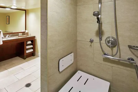 Roll-in shower and bathroom vanity in a room at Hilton Hawaiian Village Waikiki Beach Resort.