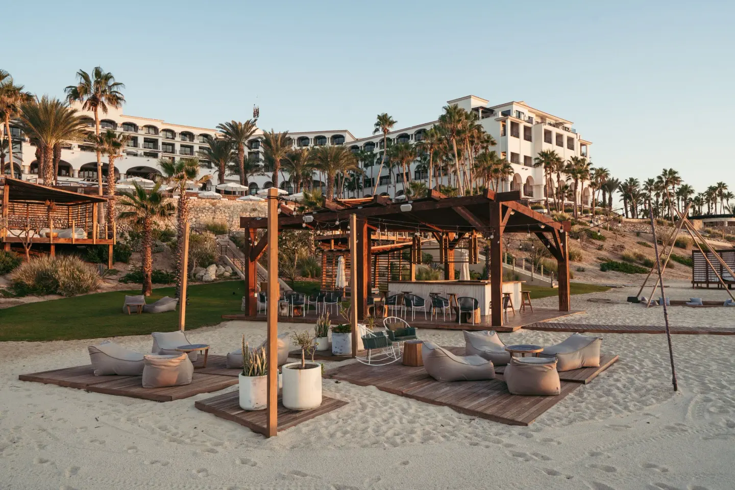 Beach lounge decks and a bar pavilion below the resort buildings at Hilton Los Cabos.