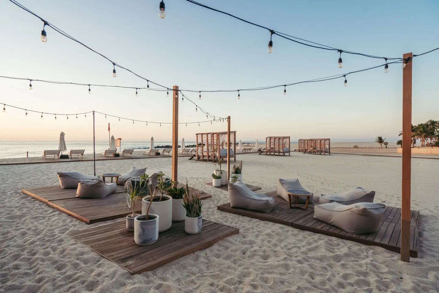 Beach lounge platforms under string lights beside the ocean at Hilton Los Cabos.