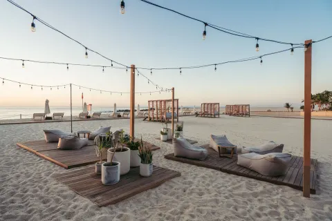 Beach lounge platforms under string lights beside the ocean at Hilton Los Cabos.