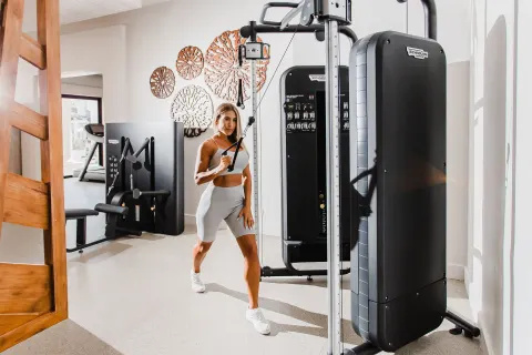 Guest using a cable machine in the fitness center at Hilton Los Cabos.