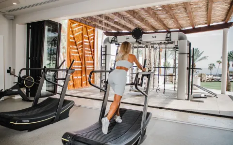 Guest on a curved treadmill beside the outdoor gym area at Hilton Los Cabos.