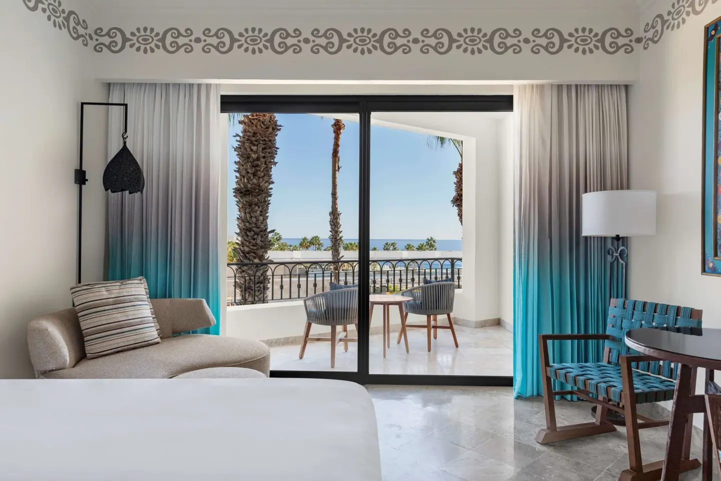 Guest room with bed, seating, balcony, and ocean view at Hilton Los Cabos.