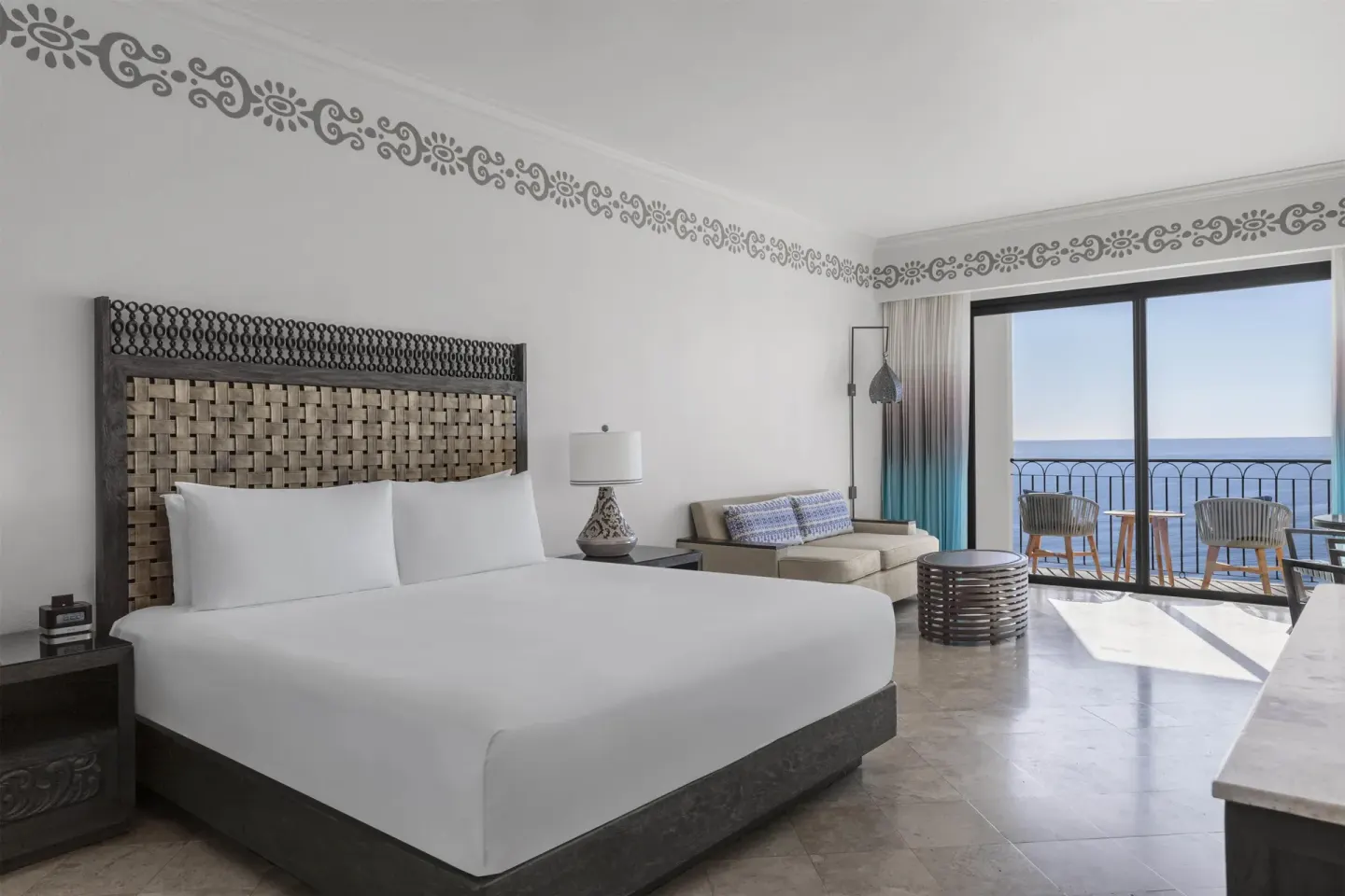 Guest room king bed with sofa seating and ocean-facing balcony at Hilton Los Cabos.