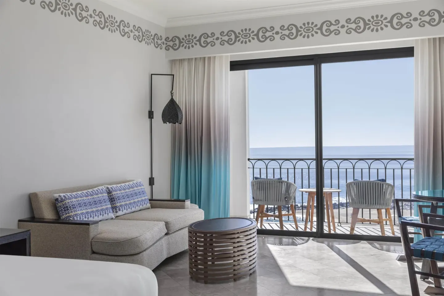 Guest room seating area and balcony chairs facing the ocean at Hilton Los Cabos.