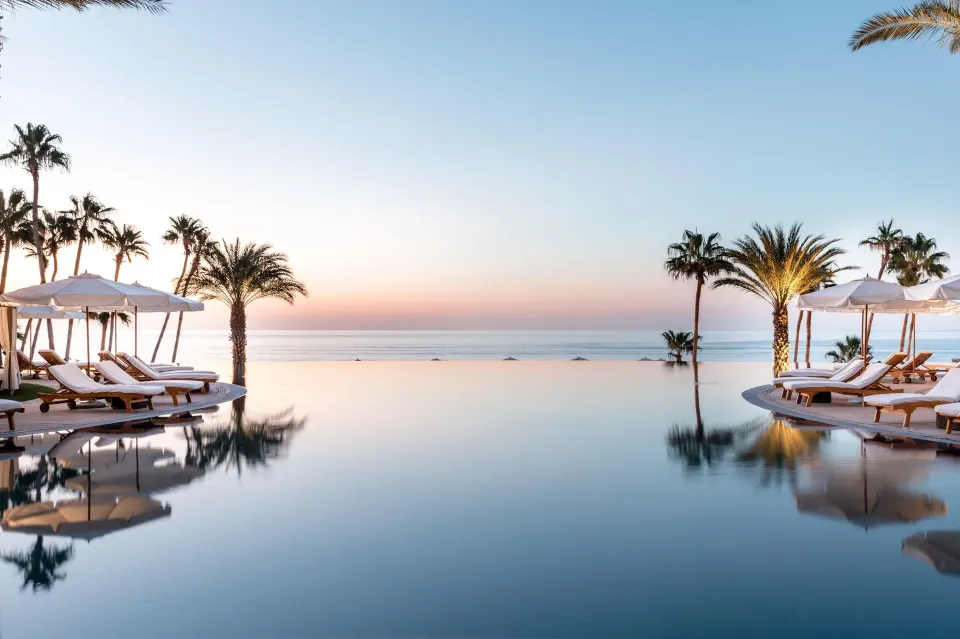 Infinity pool with loungers, umbrellas, palms and ocean horizon at Hilton Los Cabos.