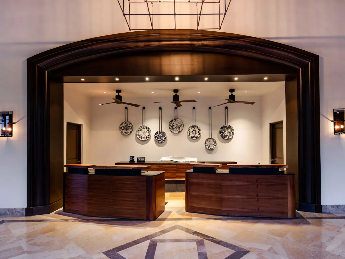 Lobby reception desks with decorative plates and arched wood trim at Hilton Los Cabos.