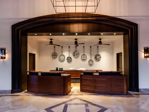 Lobby reception desks with decorative plates and arched wood trim at Hilton Los Cabos.