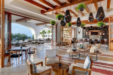 Open-air lounge with bar seating and ocean beyond at Hilton Los Cabos.