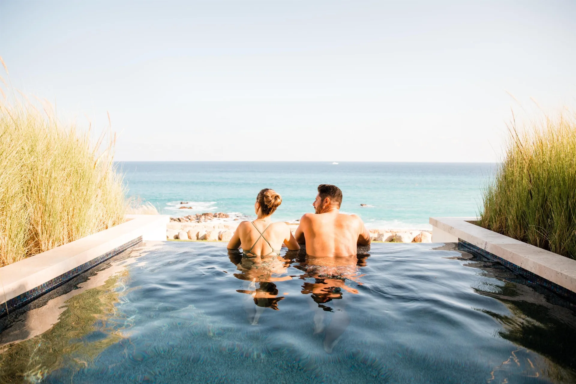 Couple in a private plunge pool overlooking the ocean at Hilton Los Cabos.
