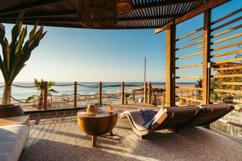 Shaded terrace lounge with ocean view and a chaise at Hilton Los Cabos.
