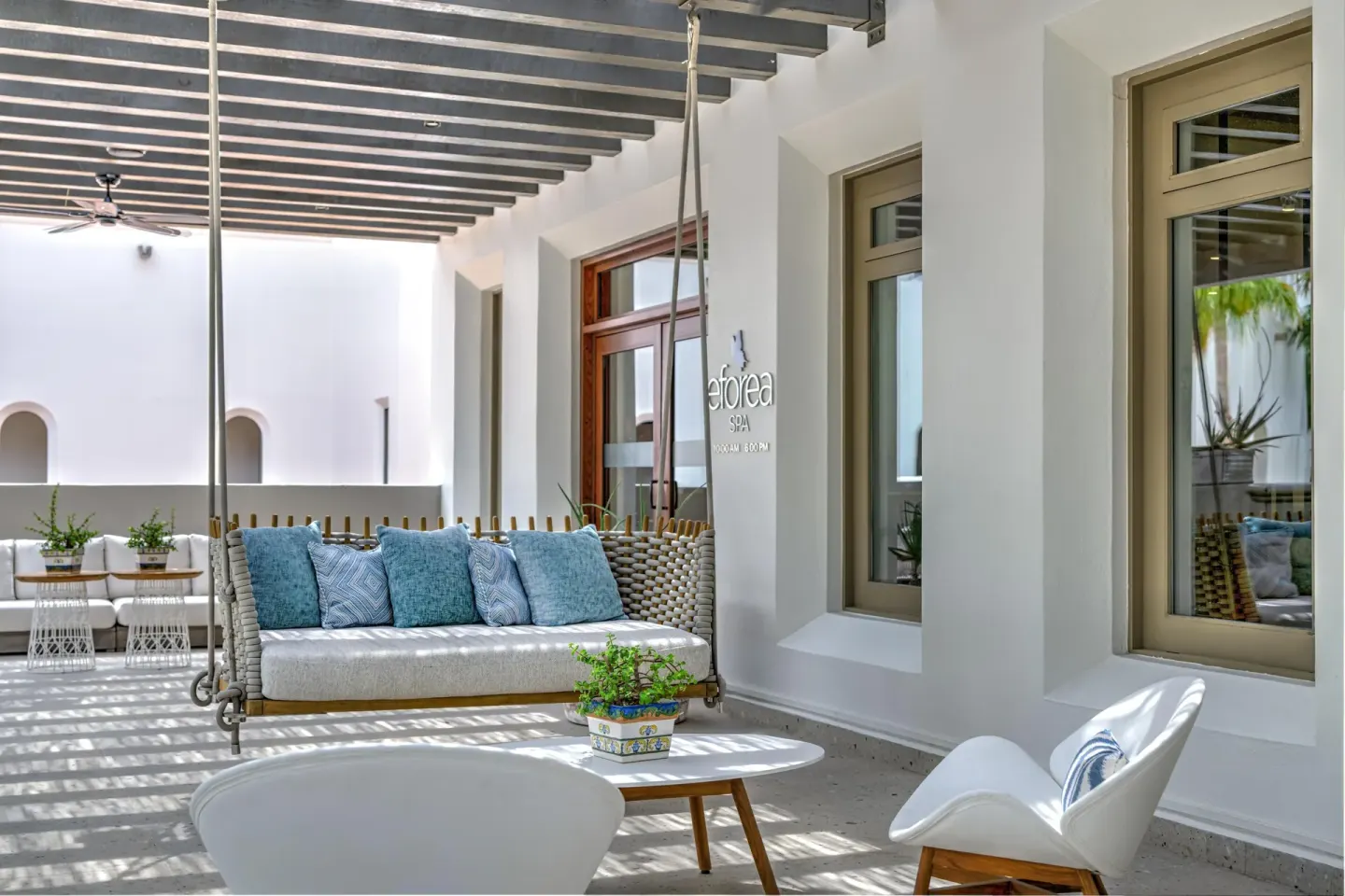Spa lounge with hanging sofa, blue pillows, and chairs at Hilton Los Cabos.