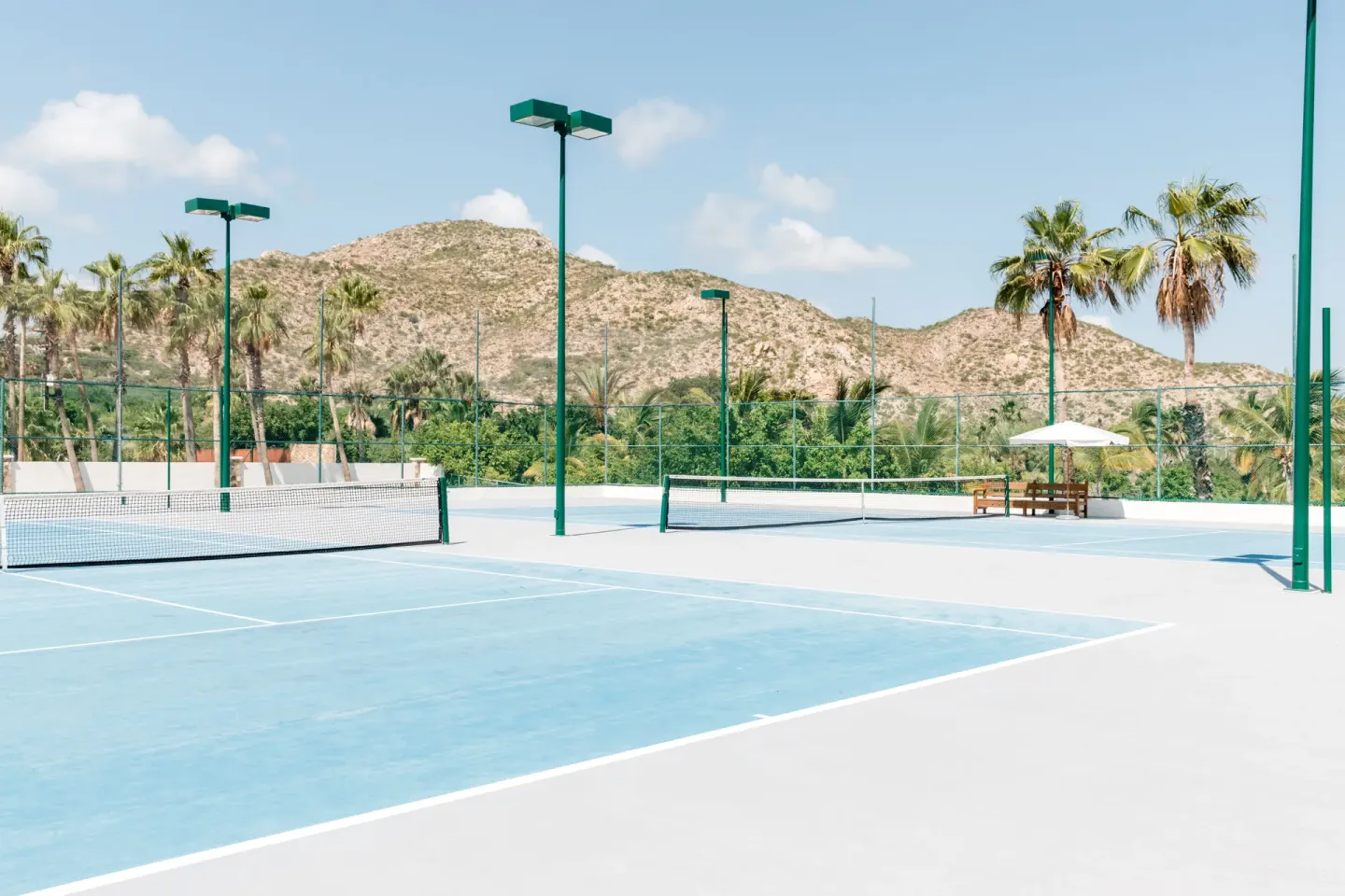 Tennis courts with palm trees and desert hills at Hilton Los Cabos.