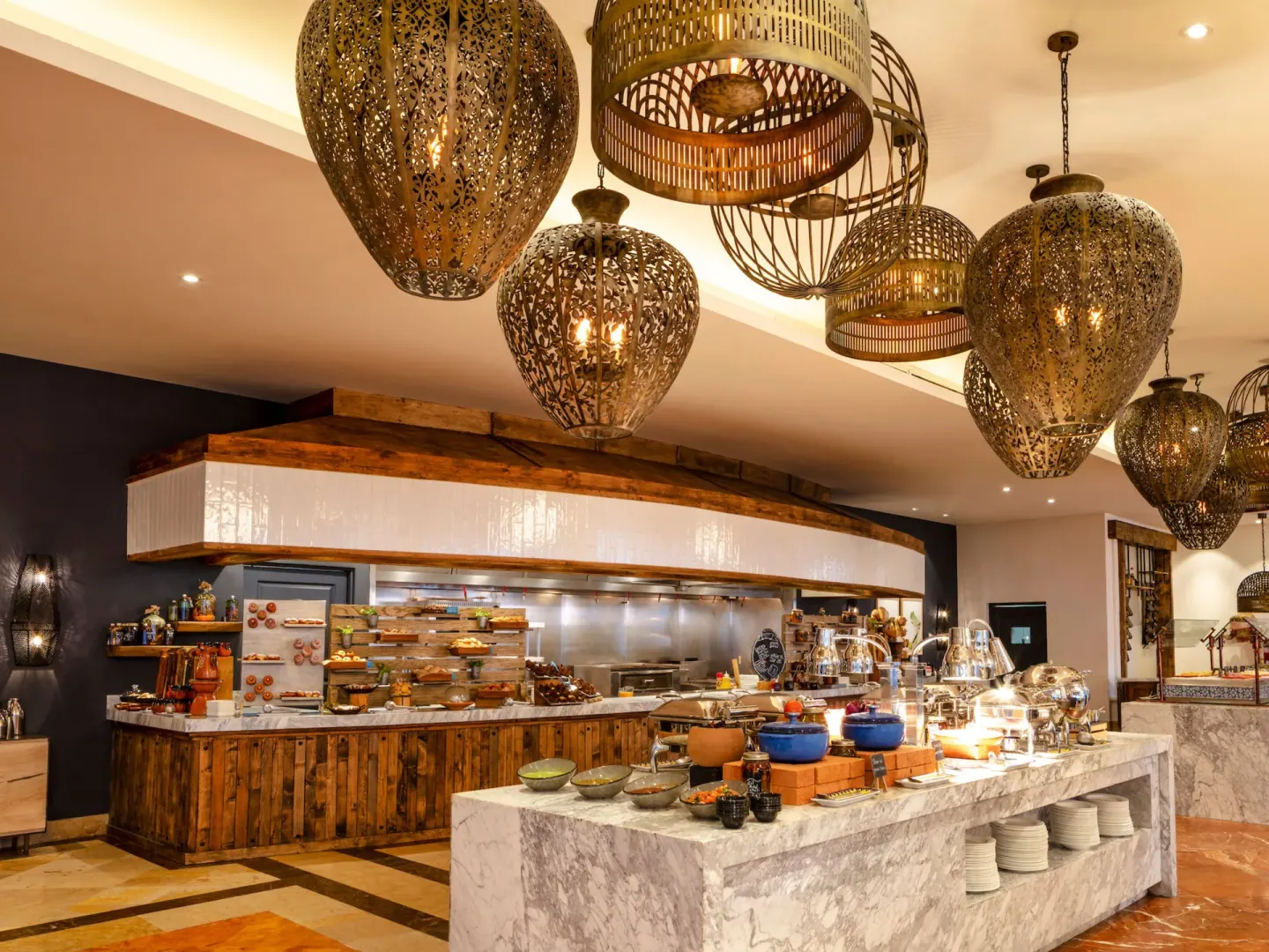 Buffet counter with warm pendant lanterns inside a dining area at Hilton Los Cabos.