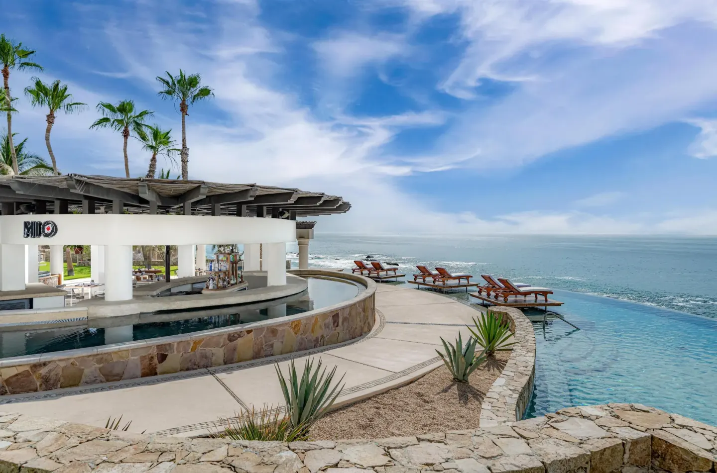 Oceanfront pool deck with Mio bar signage and lounge chairs at Hilton Los Cabos.