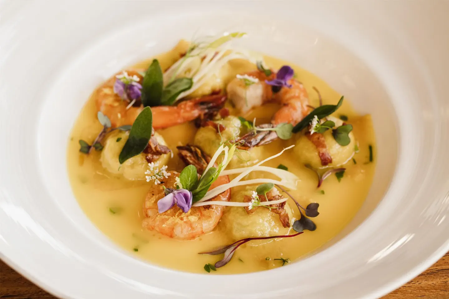 Plated shrimp dish in a yellow sauce with herbs at Hilton Los Cabos.