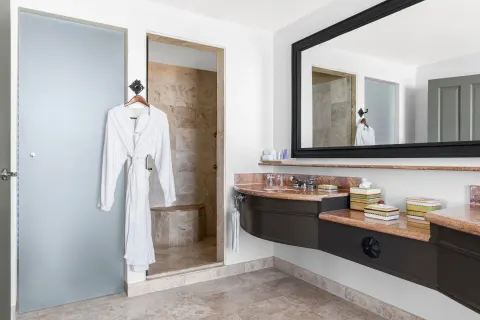 Altamar Governor Suite bathroom vanity and shower with robe at Hilton Los Cabos.