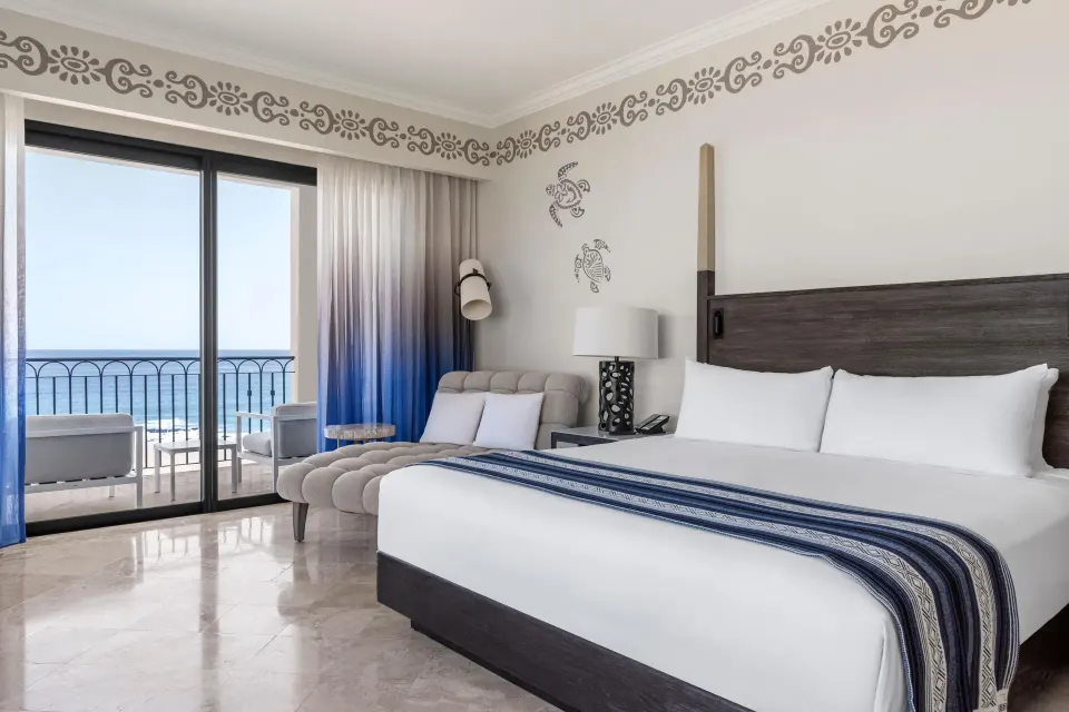 Altamar Governor Suite king bed with sitting area and ocean balcony at Hilton Los Cabos.