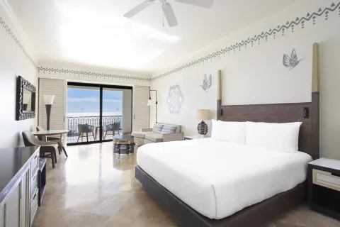 Altamar Junior Suite king bed with seating, desk, and balcony at Hilton Los Cabos.