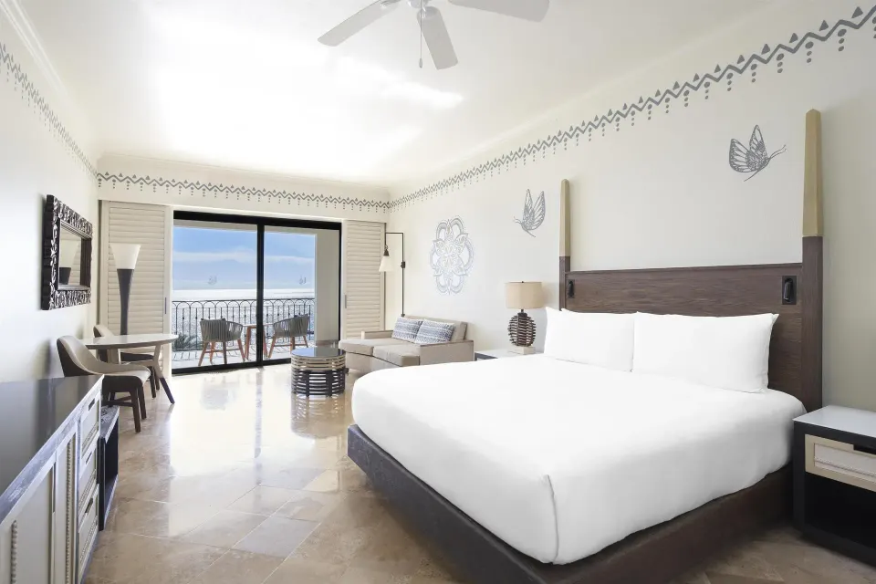 Altamar Junior Suite king bed with seating, desk, and balcony at Hilton Los Cabos.
