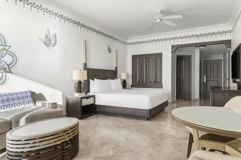 Altamar Junior Suite with king bed, sofa, coffee table, and dining table at Hilton Los Cabos.
