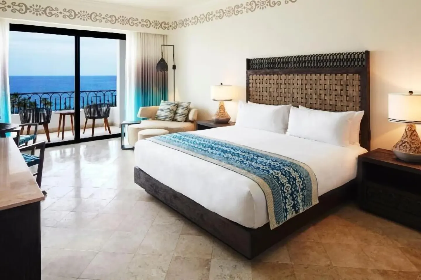 Deluxe Room Coastal Garden View king bed and balcony at Hilton Los Cabos with ocean beyond.