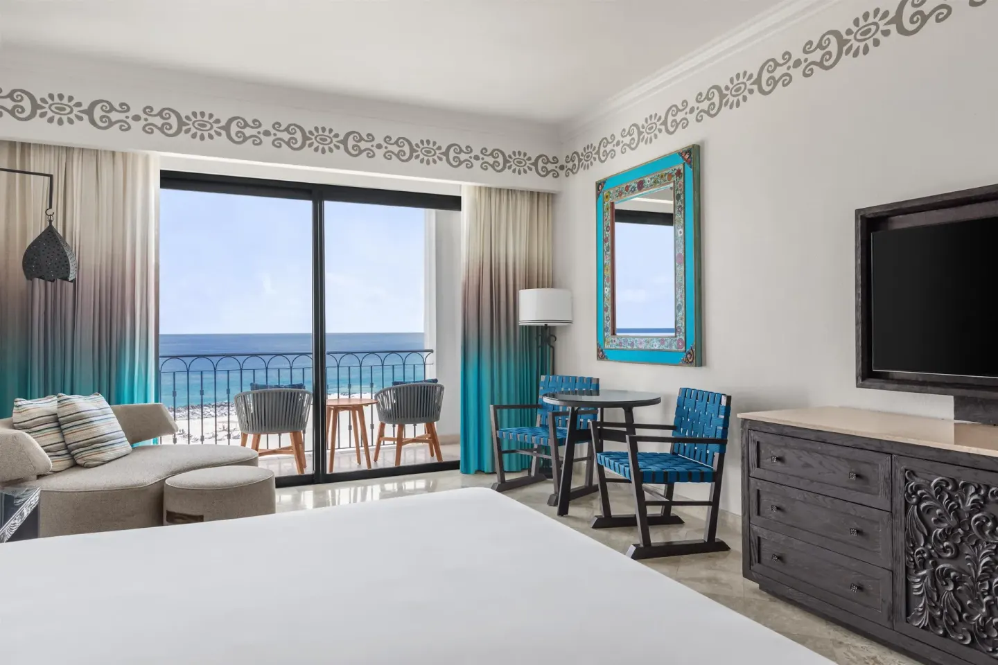 Deluxe oceanfront king room with TV, dresser, and balcony at Hilton Los Cabos.