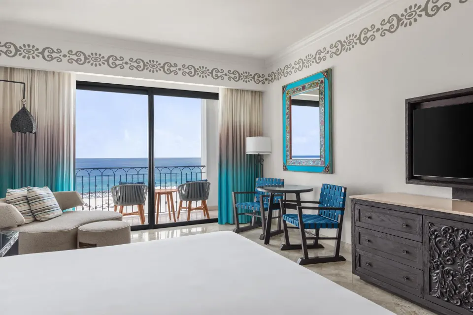 Deluxe oceanfront king room with TV, dresser, and balcony at Hilton Los Cabos.