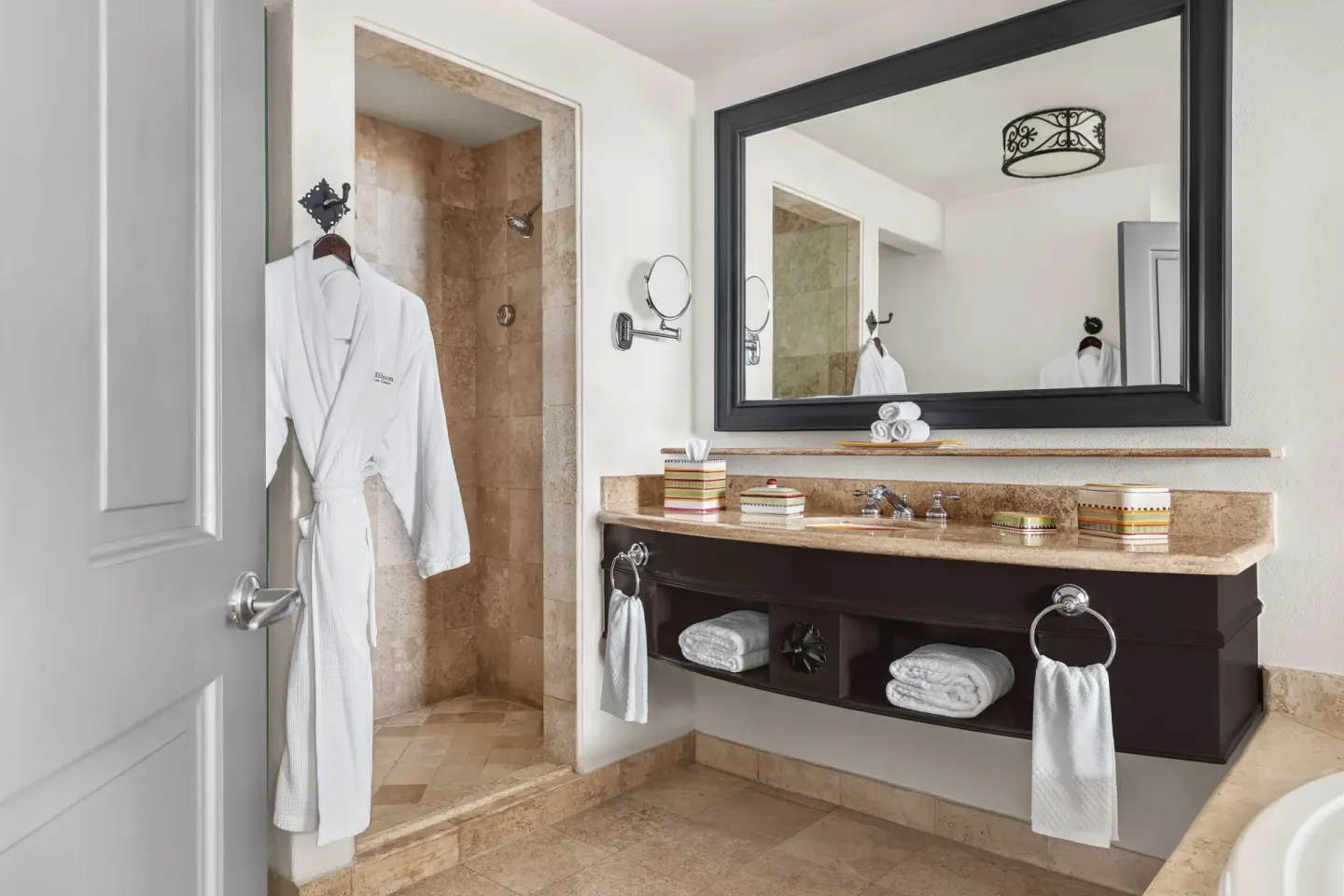 Deluxe Room bathroom with vanity, shower, and robe at Hilton Los Cabos.