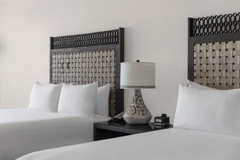 Two beds with woven headboards in a Deluxe Room at Hilton Los Cabos.
