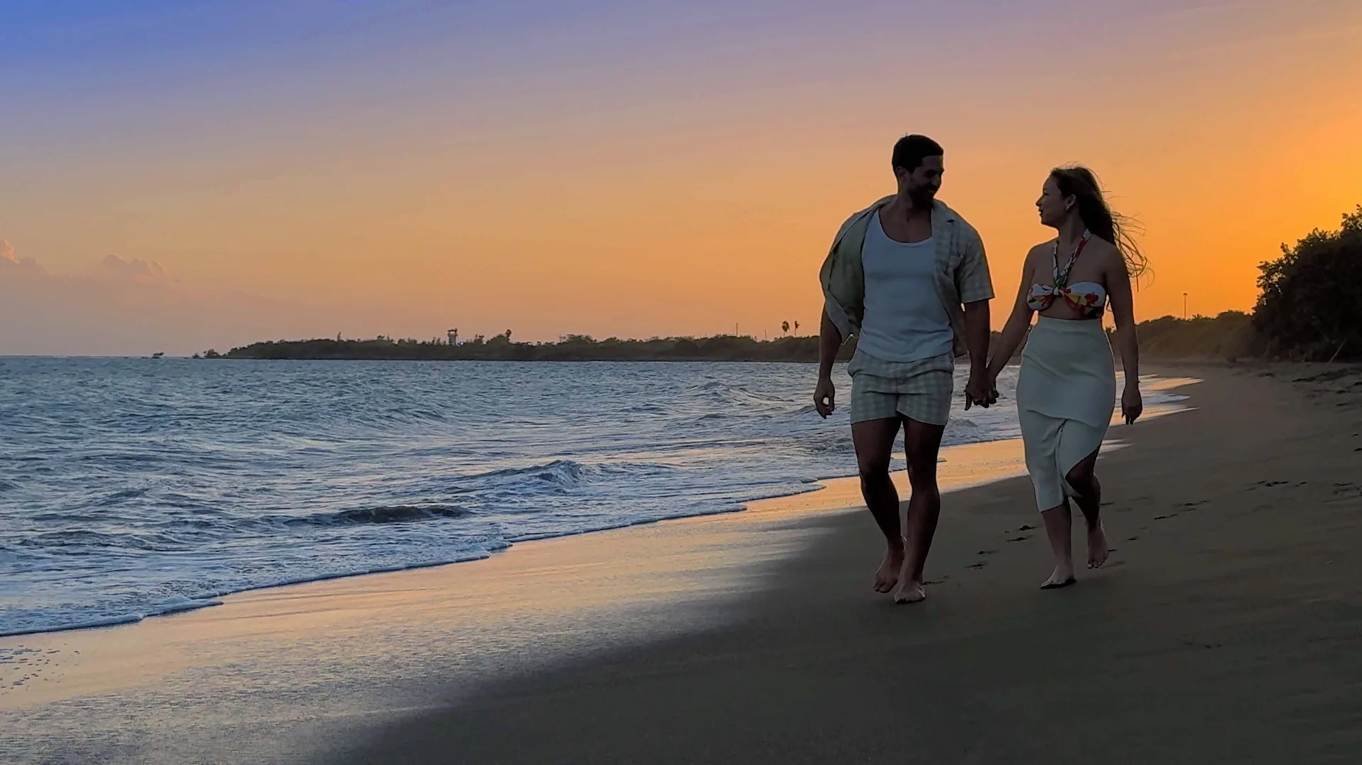 Couple walking on the beach at sunset near Hilton Ponce Golf & Casino Resort.