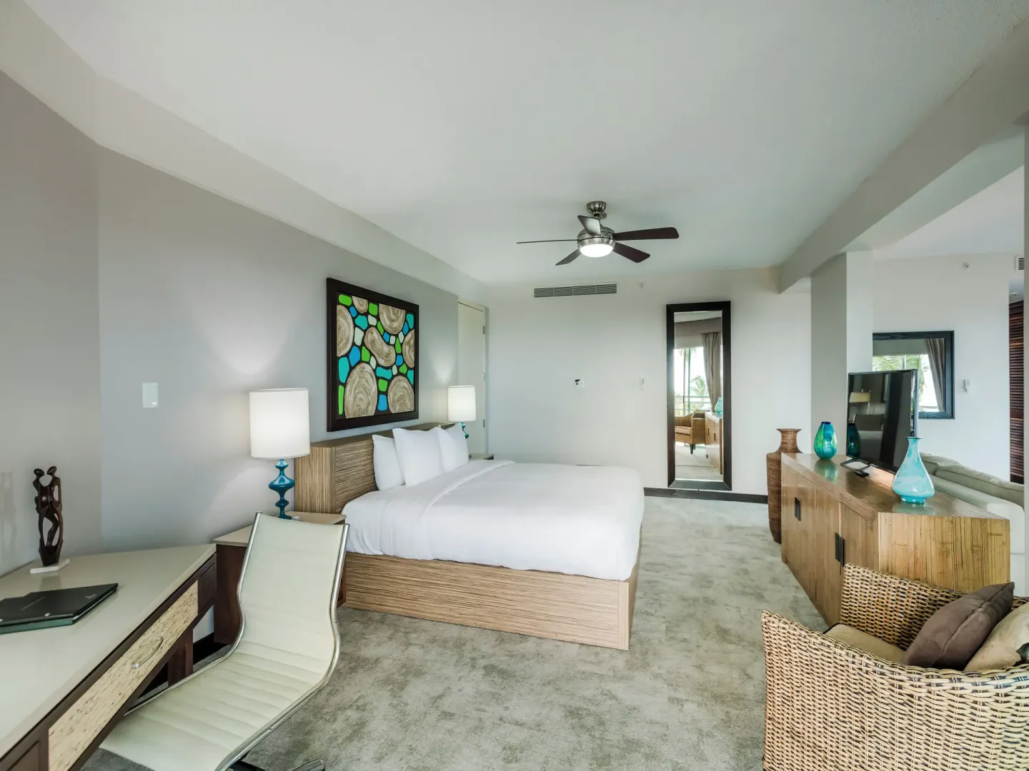 King-bed guest room with desk, seating, and woven furniture at Hilton Ponce Golf & Casino Resort.