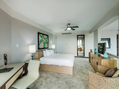King-bed guest room with desk, seating, and woven furniture at Hilton Ponce Golf & Casino Resort.