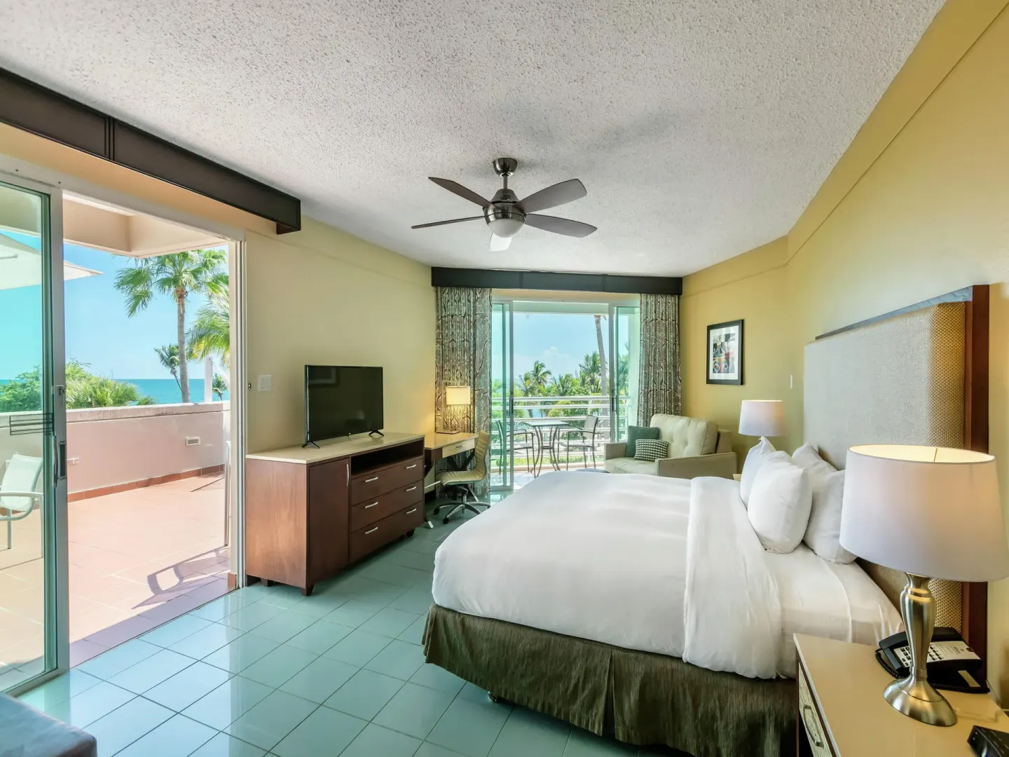 King-bed guest room with ocean-facing balcony at Hilton Ponce Golf & Casino Resort.