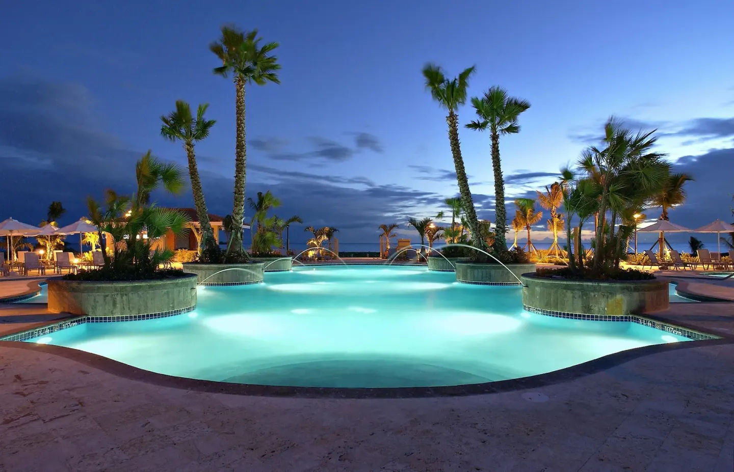 Illuminated pool at dusk with palms at Hilton Ponce Golf & Casino Resort.