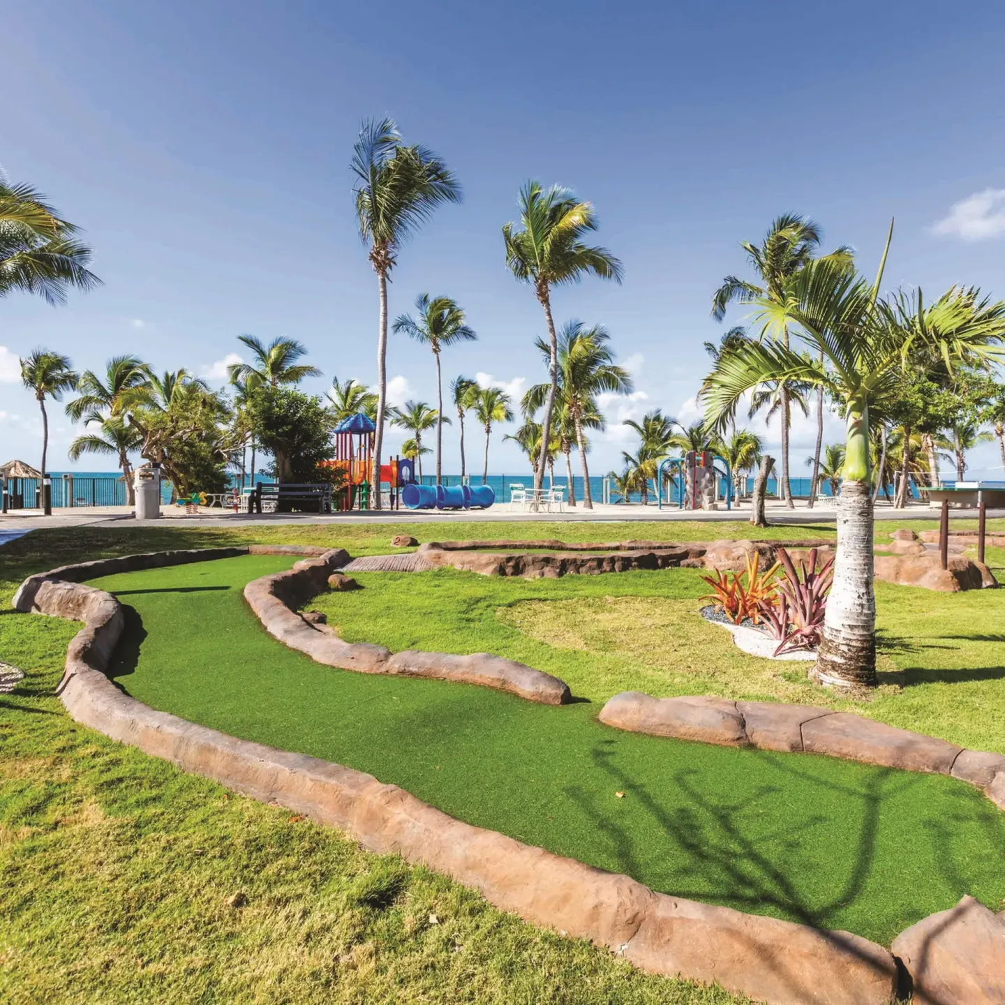 Mini-golf green near palms and playground at Hilton Ponce Golf & Casino Resort.