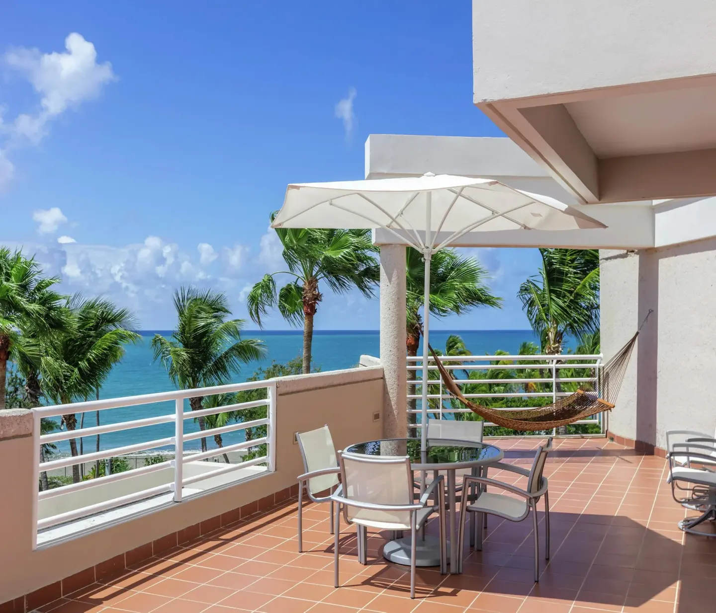 Ocean-view terrace with umbrella, table and hammock at Hilton Ponce Golf & Casino Resort.