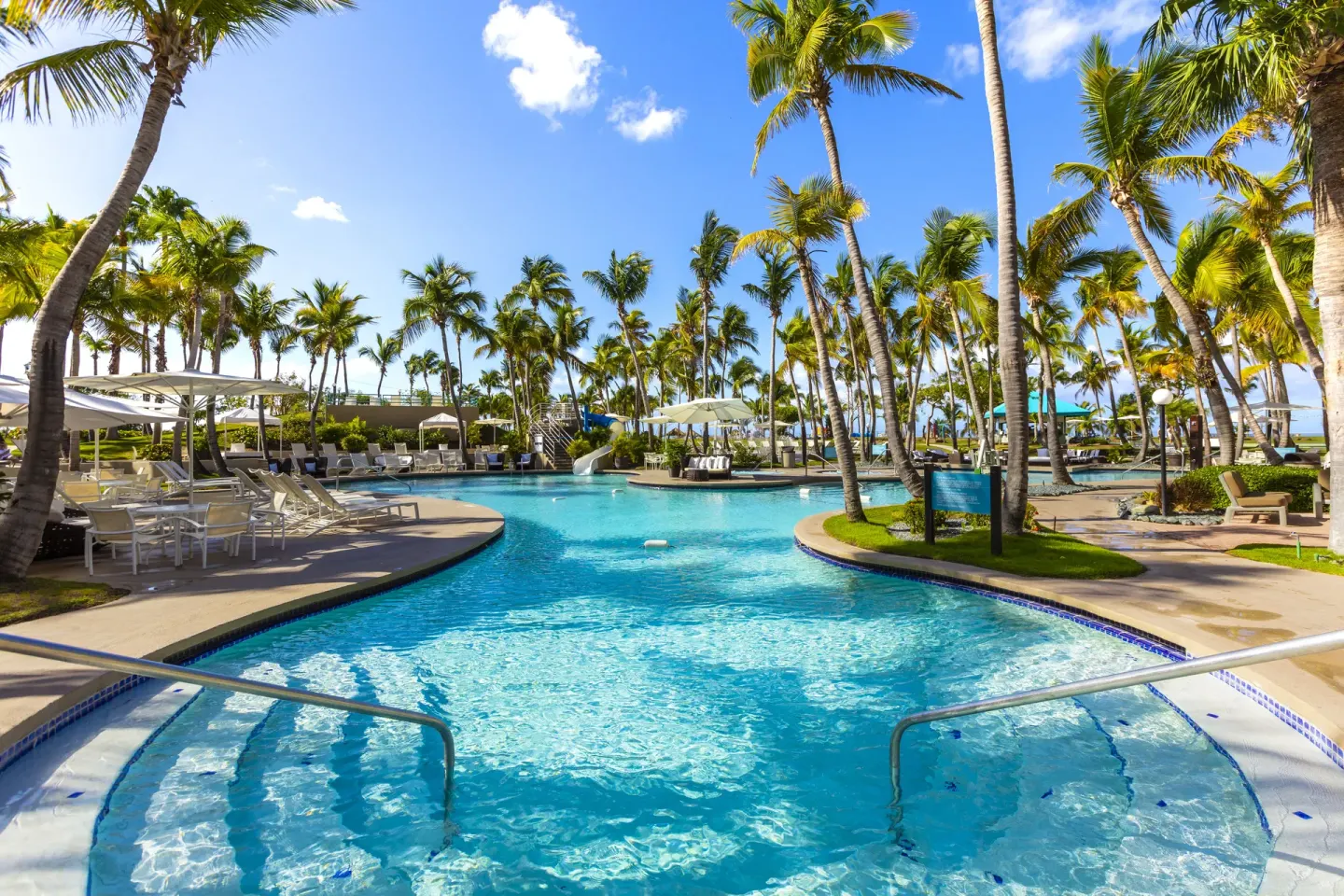 Pool entry with palm trees and shaded seating at Hilton Ponce Golf & Casino Resort.