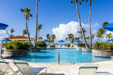 Pool with lounge chairs, palms, and ocean view at Hilton Ponce Golf & Casino Resort.